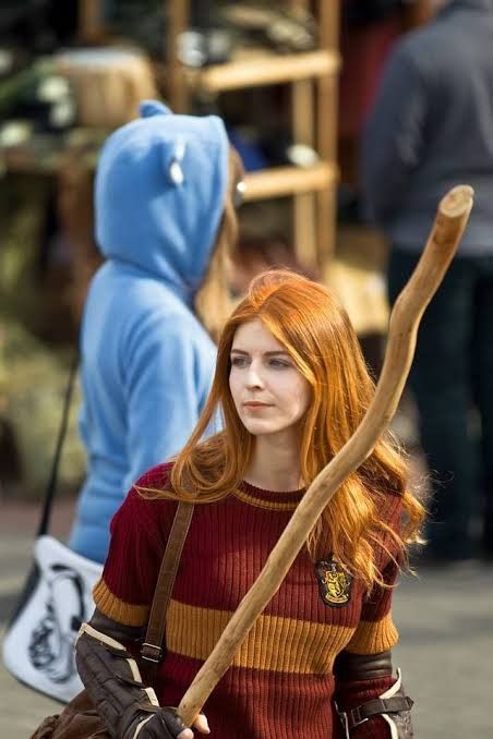 a woman with red hair is holding a stick