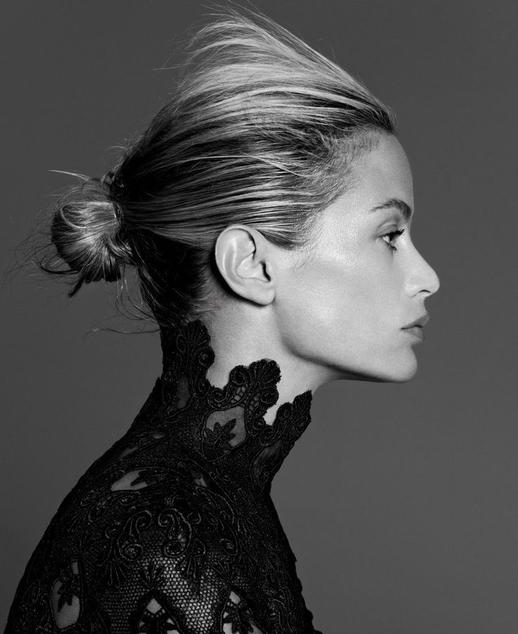 a black and white photo of a woman with her hair in a high bun up