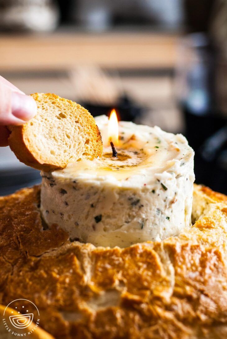 someone lighting a candle on top of some bread