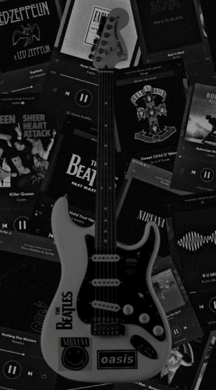 a black and white photo of an electric bass guitar surrounded by music cd's