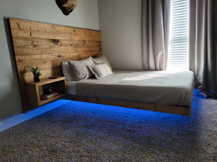 a bedroom with a bed, nightstands and blue lights on the carpeted floor