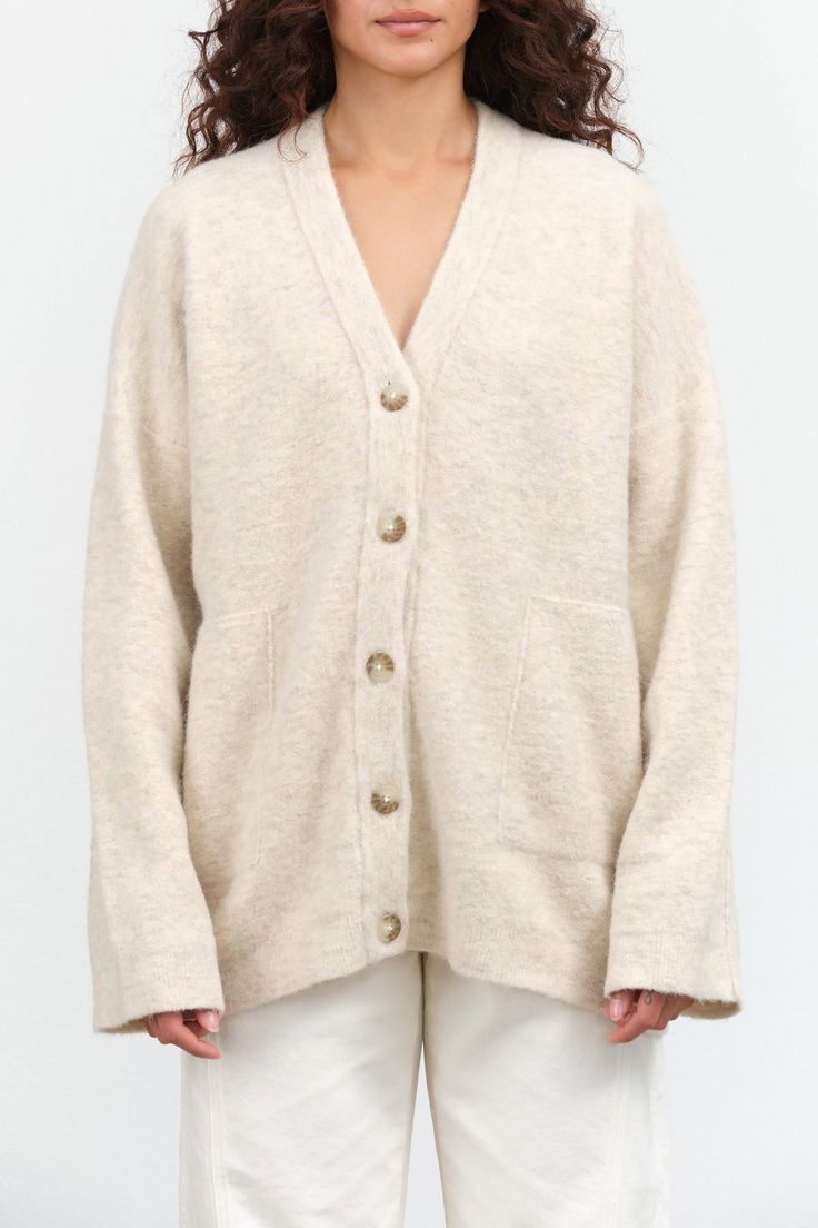 The Fleece Cardigan is an oversized button up cardigan with an elegant drop shoulder and v-neck design, and two large side pockets. This cozy cardigan is perfect for going into fall and winter months. Soft Knit V-neck Cardigan For Daywear, Cozy Oversized V-neck Outerwear, Oversized Cozy V-neck Outerwear, Oversized Cozy Outerwear With V-neck, Cream V-neck Outerwear With Pockets, Neutral V-neck Cardigan For Work, Oversized Soft Knit Button-up Cardigan, Cozy Button-up Cardigan For Loungewear, Oversized Beige Cardigan With Button Closure