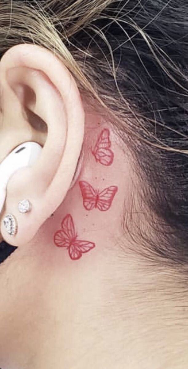 a woman's behind the ear tattoo with red butterflies