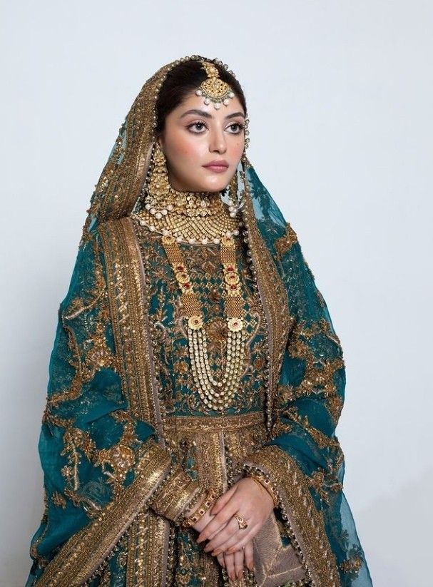 a woman in a green and gold wedding dress standing with her hands on her hips