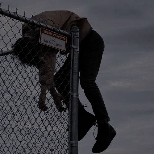 a man climbing up the side of a fence with his foot on top of it