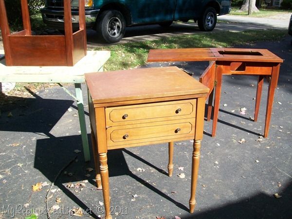 three small wooden tables sitting next to each other on the ground in front of a truck