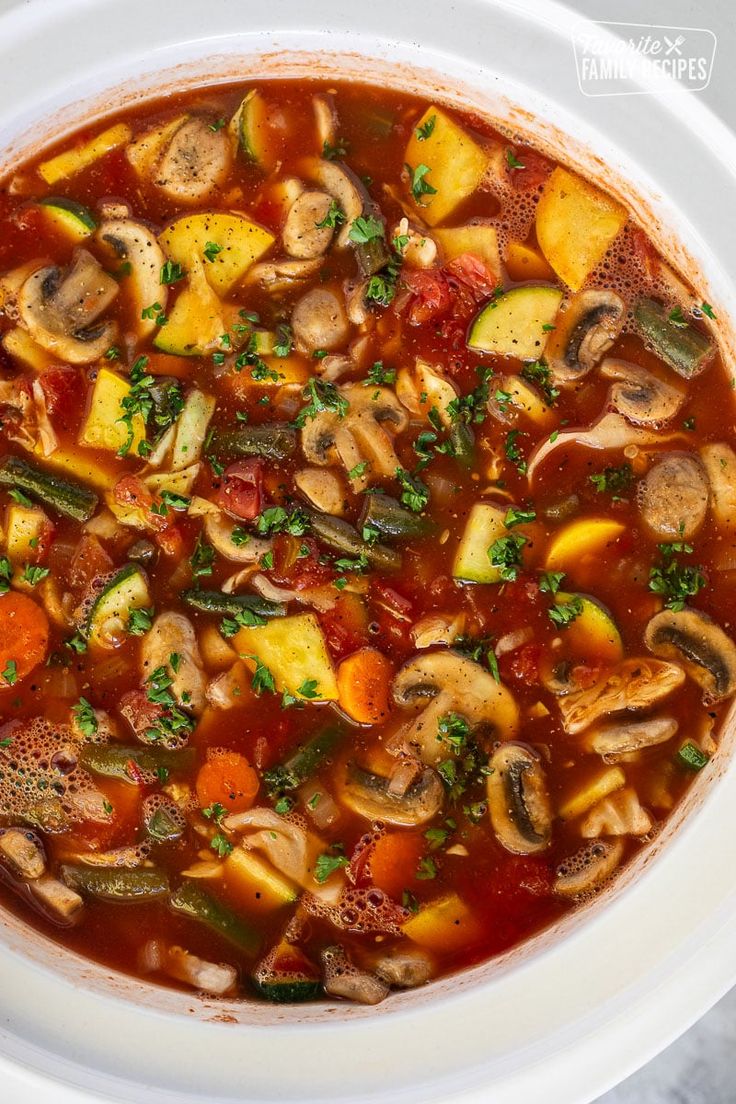 a white bowl filled with vegetable soup on top of a table