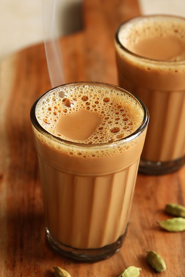 two glasses filled with coffee sitting on top of a wooden table