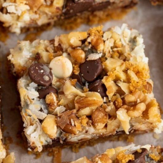 several pieces of dessert sitting on top of a piece of parchment paper covered in nuts and chocolate