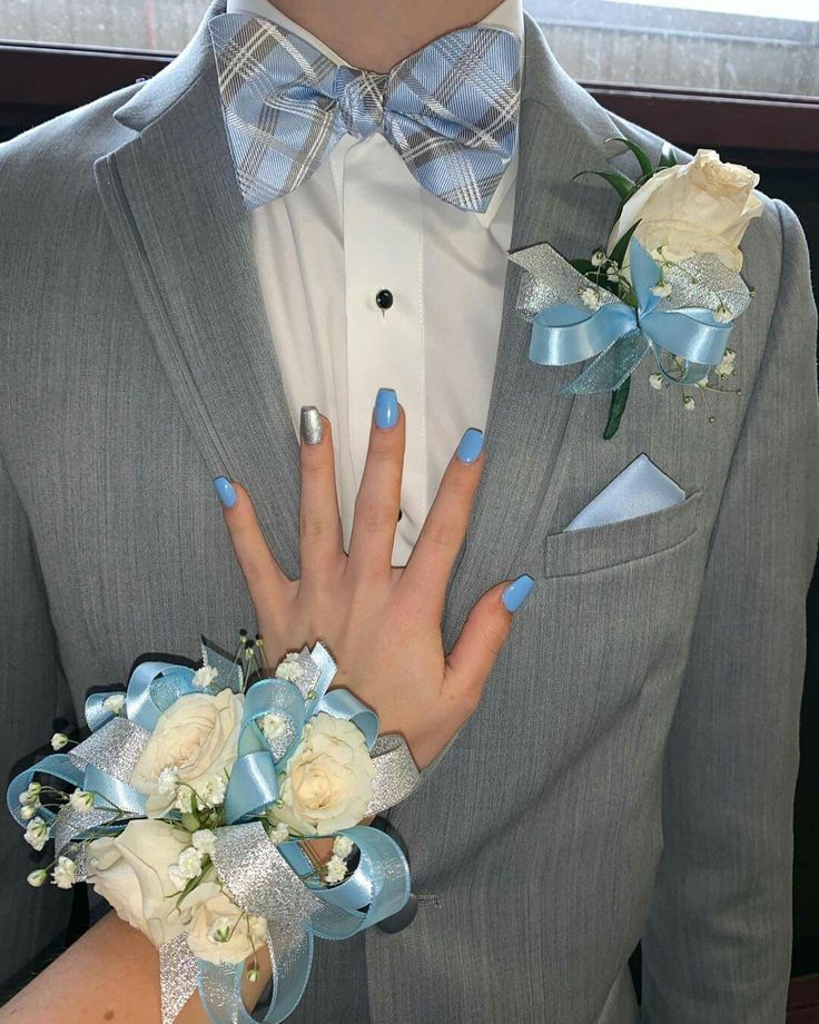 a man in a gray suit with blue and white flowers on his lapel flower