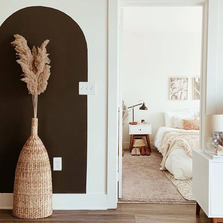 a room with a bed and a vase on the floor in front of an open door