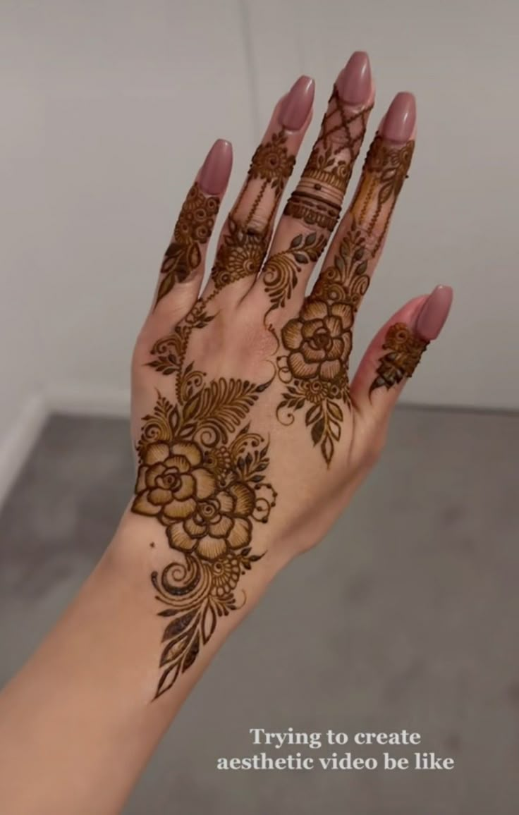 a woman's hand with henna tattoos and flowers on her hands, showing the intricate