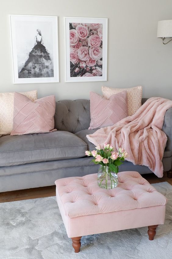 a living room with grey couches and pink pillows