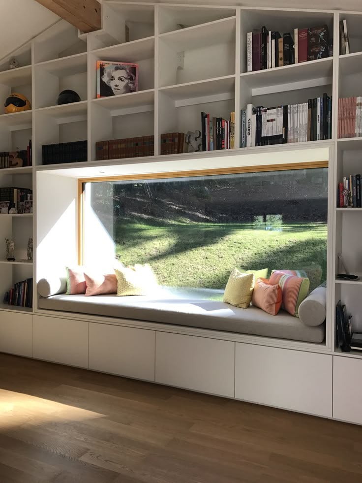 a window seat in front of a book shelf filled with books