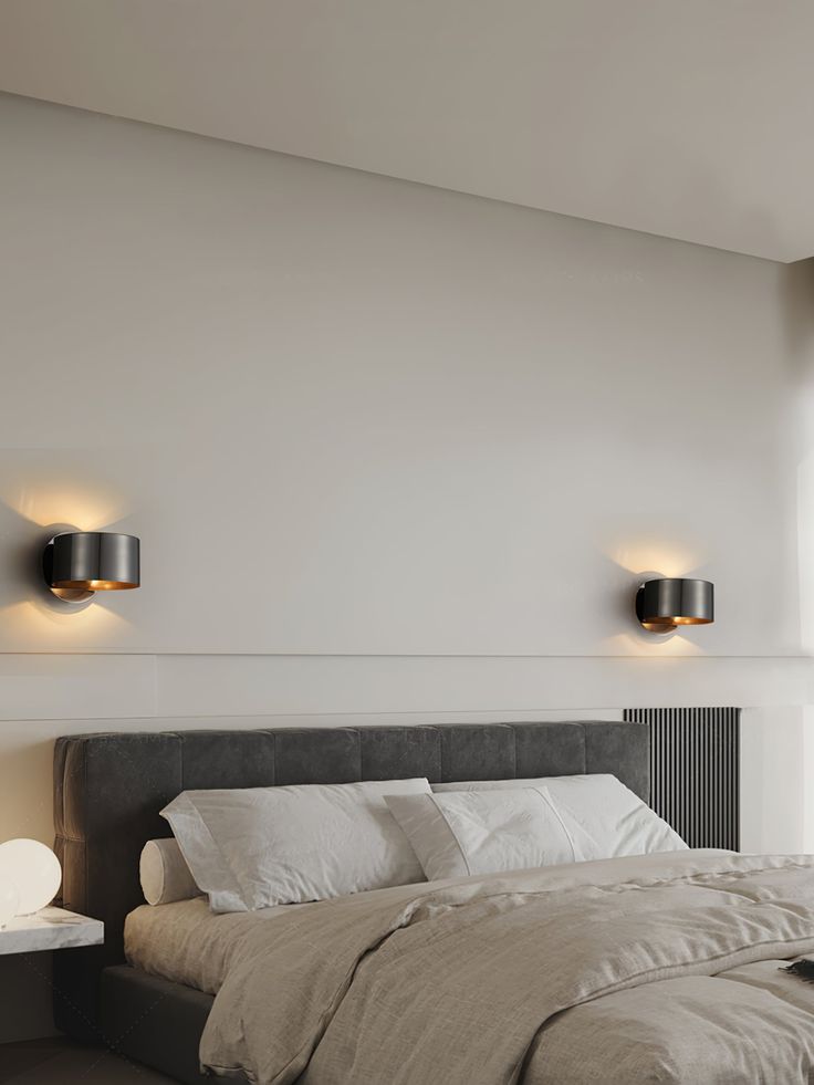 there is a bed with two lights on the wall above it