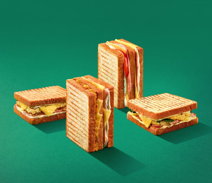 four sandwiches stacked on top of each other with cheese and bacon in between the two halves