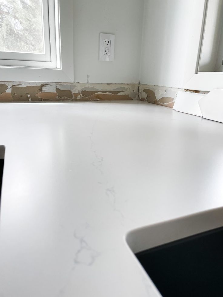 a white counter top sitting under a window