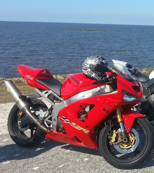 a red motorcycle parked next to the ocean