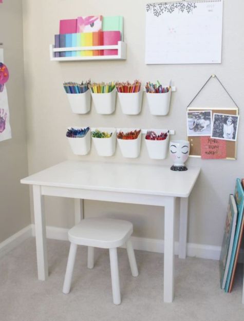 a white table topped with lots of cups filled with crayons