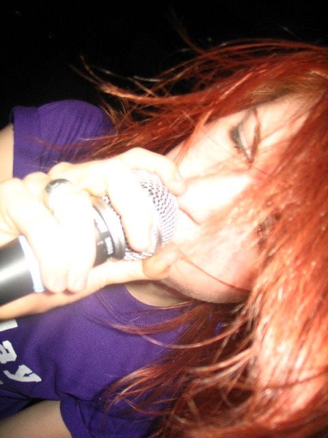 a woman with red hair is singing into a microphone