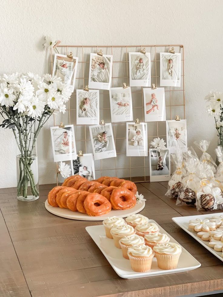 a table topped with lots of pastries and cupcakes next to vases filled with flowers