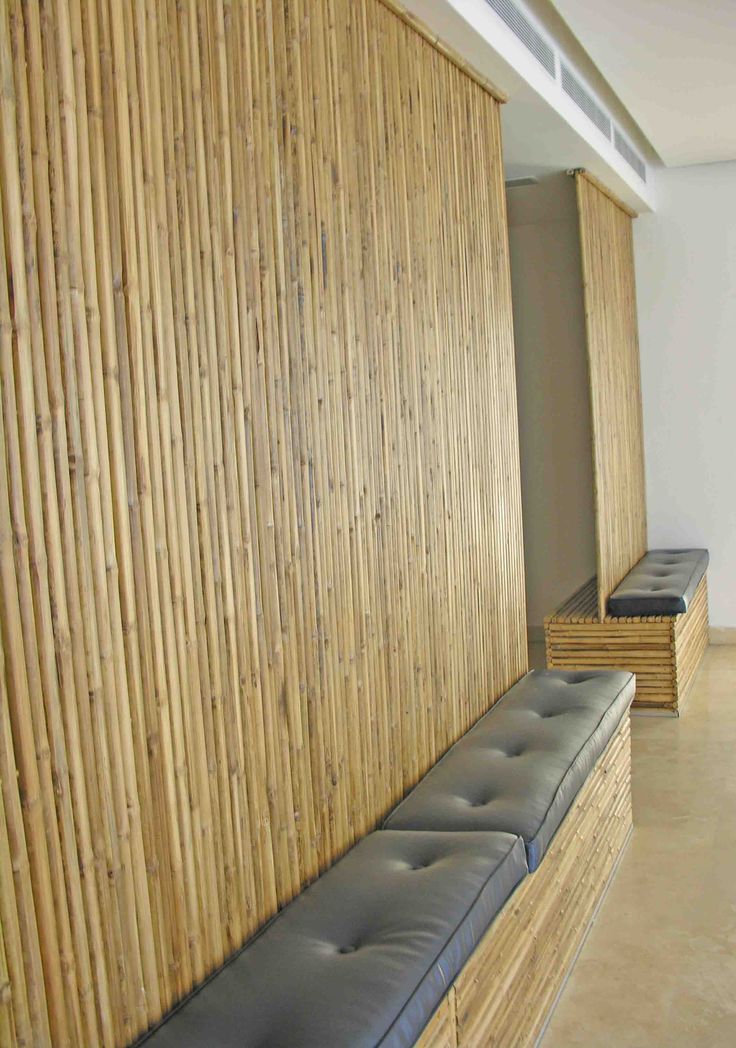 a bench sitting in front of a wooden wall with bamboo slats on the walls