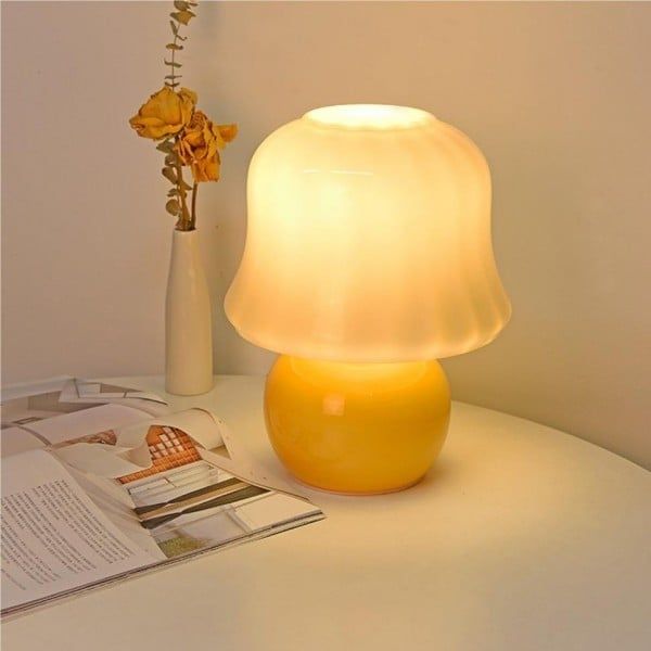 a yellow lamp sitting on top of a table next to a vase with flowers in it