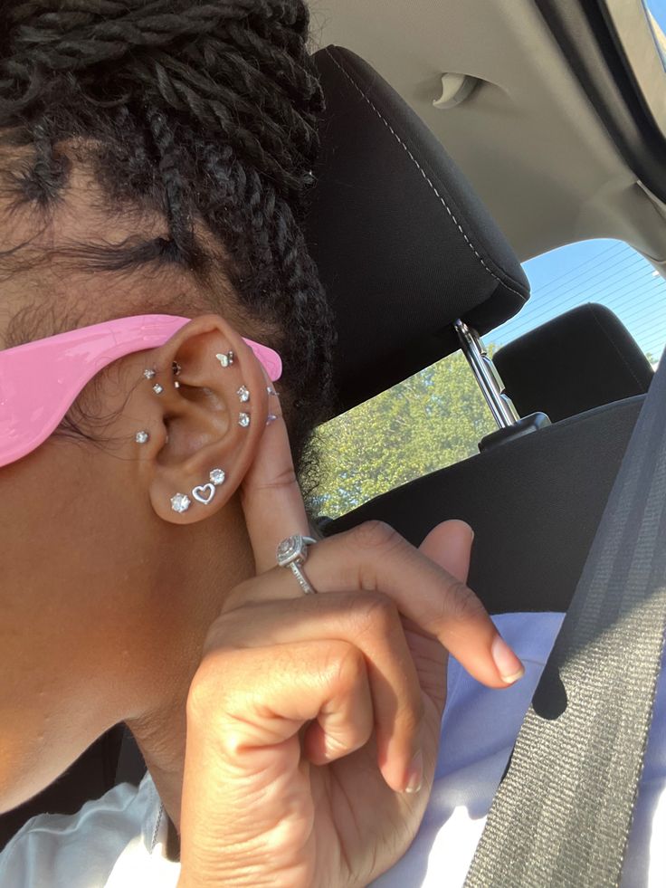 a woman with ear piercings sitting in the back seat of a car