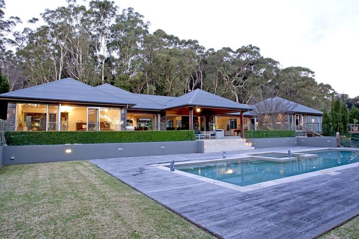 a house with a pool in front of it and trees around the back yard area