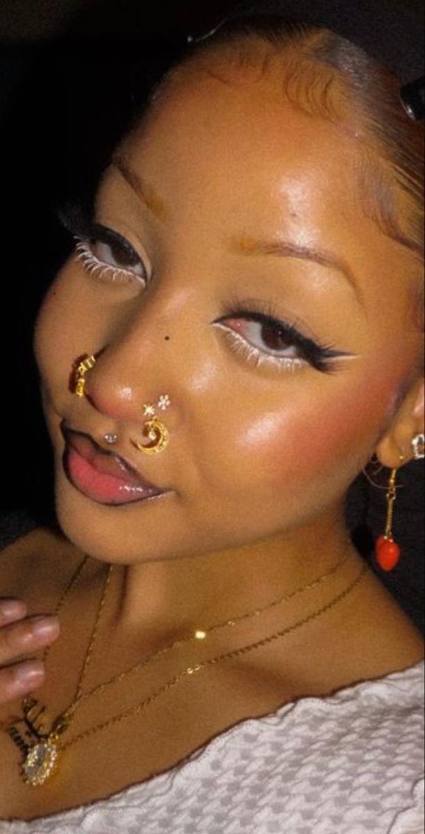 a woman with gold nose rings and piercings on her face is posing for the camera