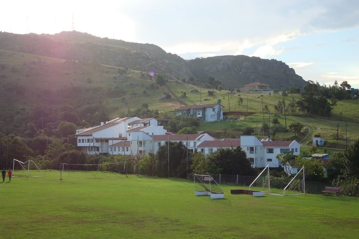 a soccer field with houses in the background and people playing on the grass near by