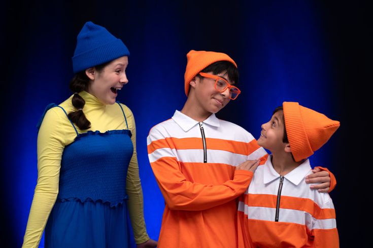 three people standing next to each other in front of a blue background wearing orange and white striped shirts