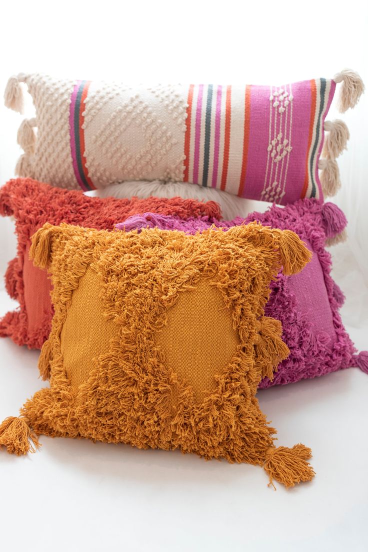 three pillows with tassels on them are lined up against a white background,