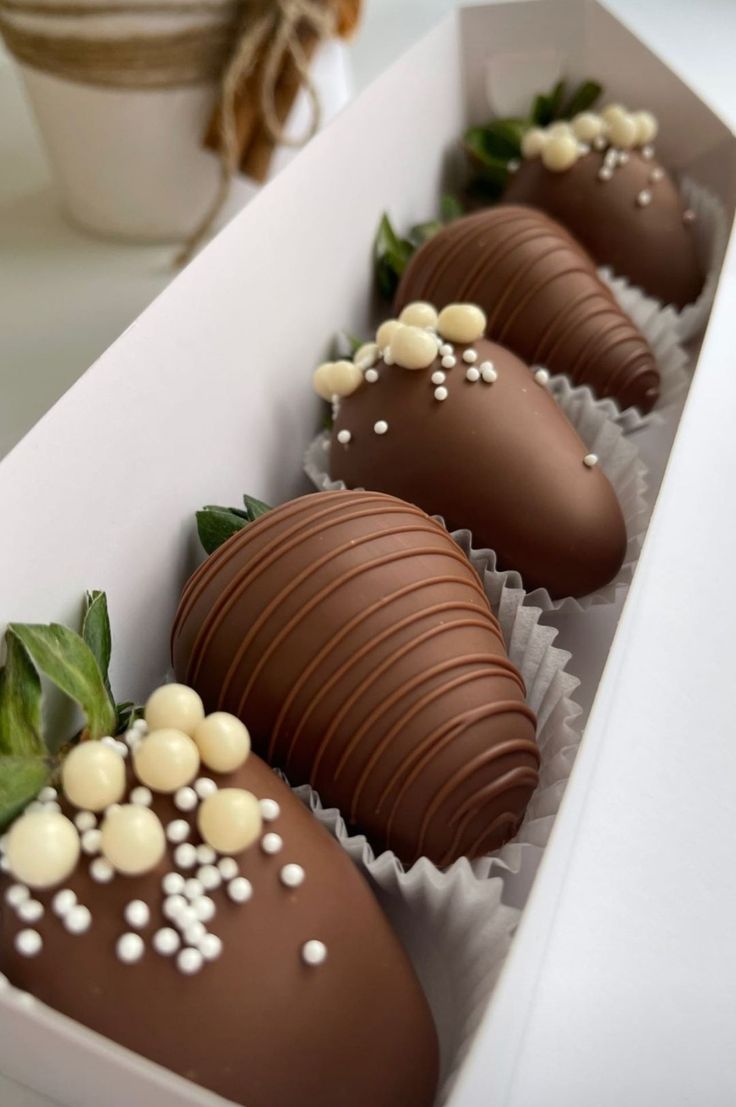 three chocolate covered strawberries in a white box