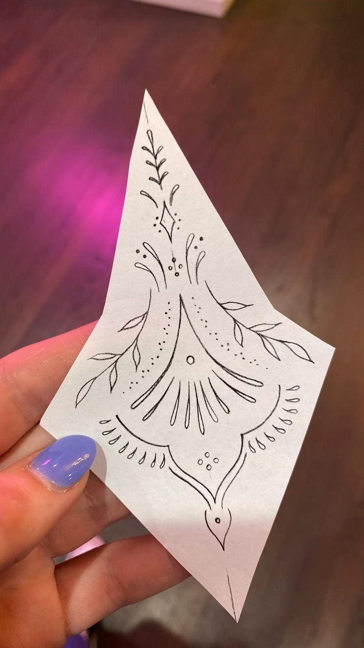 someone holding up a piece of paper with designs on it