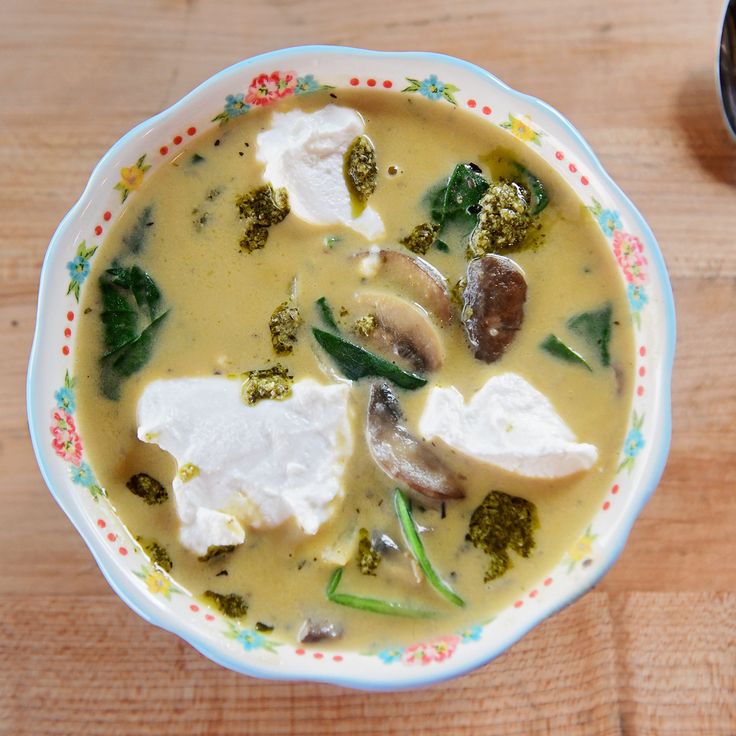 a bowl of broccoli and tofu soup with a spoon on the side