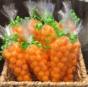 some carrots wrapped in plastic sitting on a table next to a basket with green ribbon