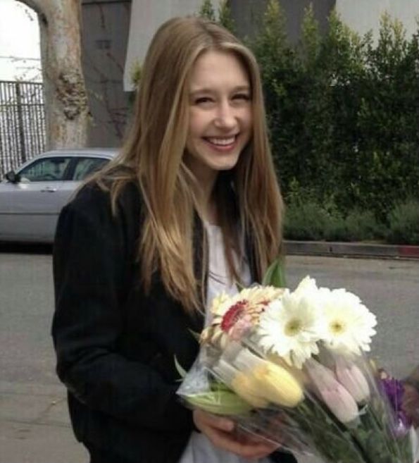 a woman is holding a bouquet of flowers in her hands and smiling at the camera