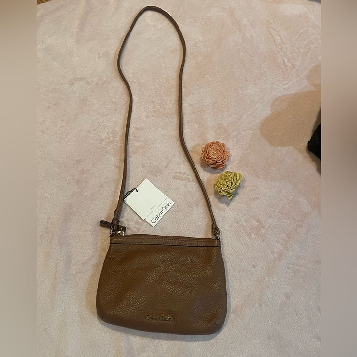 This Small Calvin Klein Crossbody Is So Cute And Brand New!! A Brown Color That Goes Well With Anything. 100% Leather Closure Type - Zipper Lining - Polyester Pockets: 1 Interior Slip, 1 Interior Zip Pebble Leather Crossbody Bag Width 8.5 Inch 6 Inch Height 2.6 Inch Depth 23 Inch Strap Drop Casual Calvin Klein Shoulder Bag, Calvin Klein Bags, Chestnut Leather, Calvin Klein Bag, Vintage Calvin Klein, Zip Purse, Brown Purses, Cross Bag, Black Crossbody