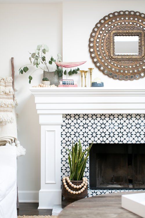 a living room with a fireplace, mirror and potted plant on the mantel