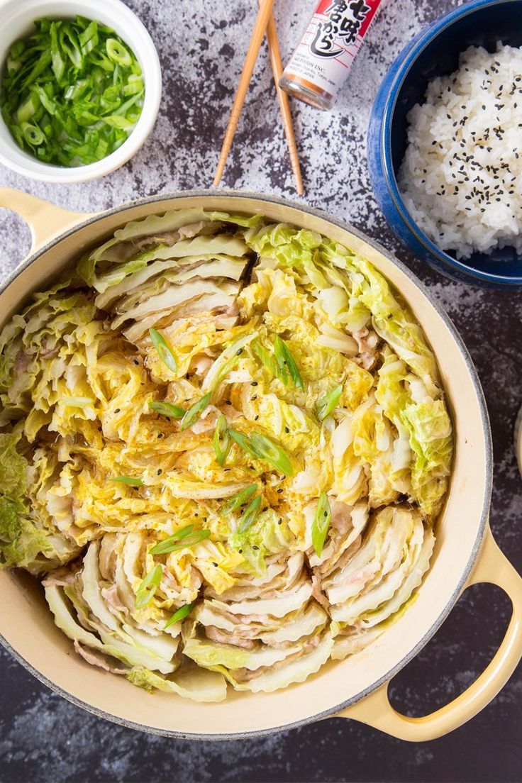 an image of food in a pan with chopsticks and rice on the side