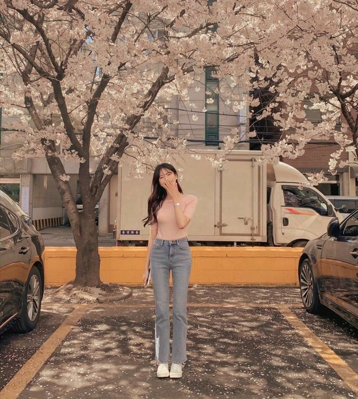 a woman standing in front of a tree with pink flowers