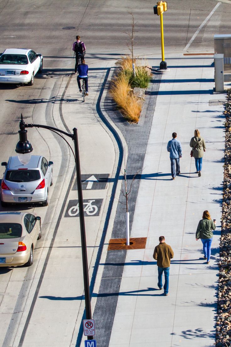 several people walking down the sidewalk on a sunny day