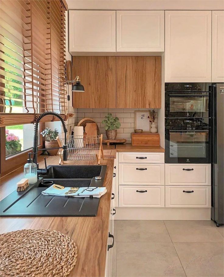 a kitchen with white cabinets and wooden counter tops, along with a black refrigerator freezer