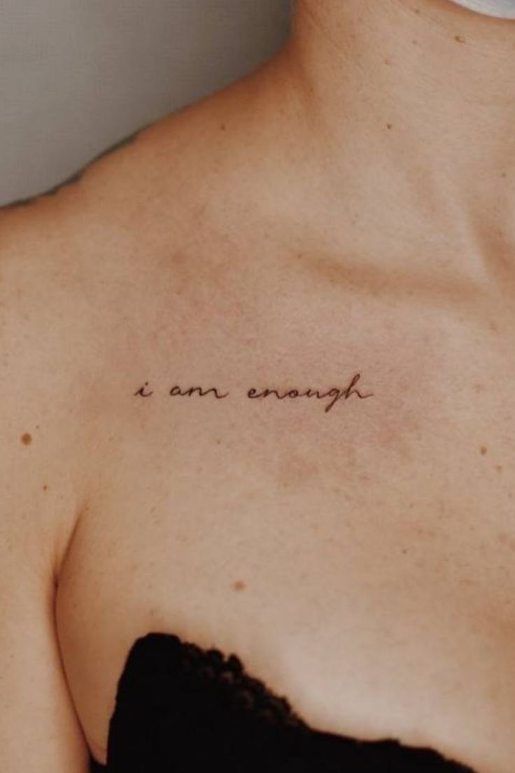 a woman's chest with the words i am enough written in cursive ink