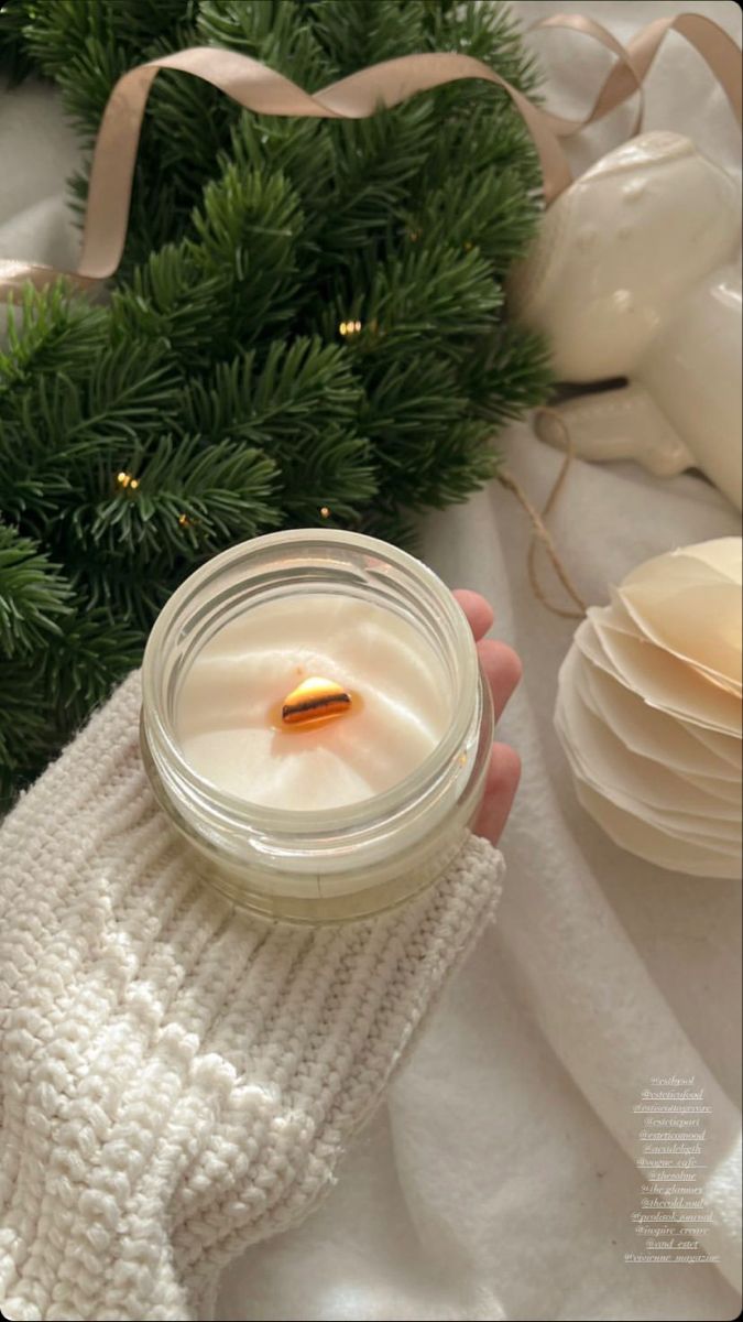 a person holding a jar with a candle in it next to a christmas tree and other decorations