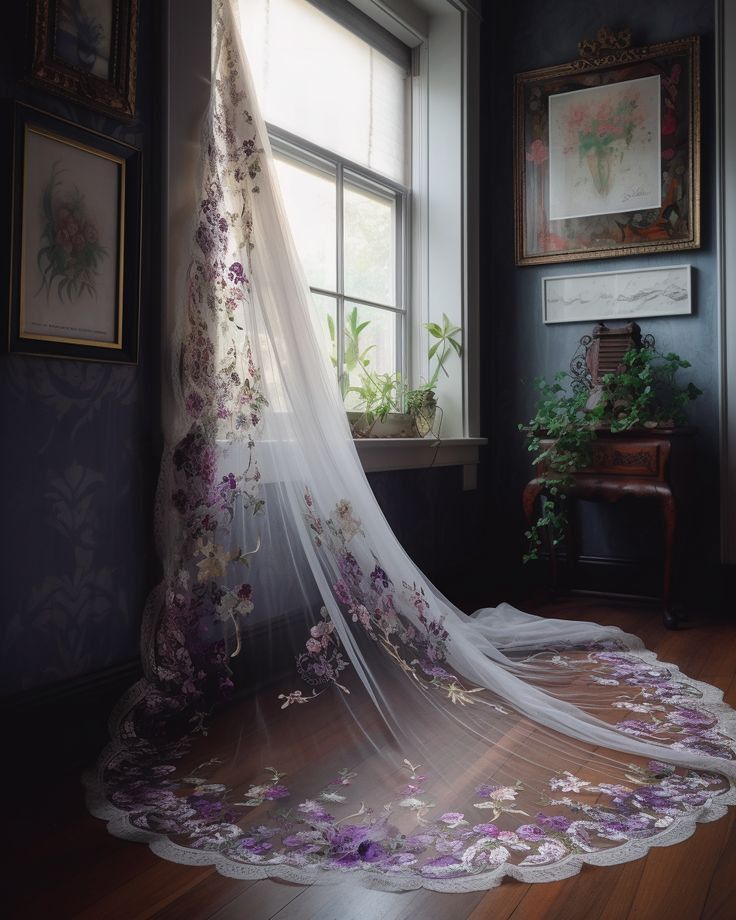 a white veil hanging from the side of a window next to a flower covered bed