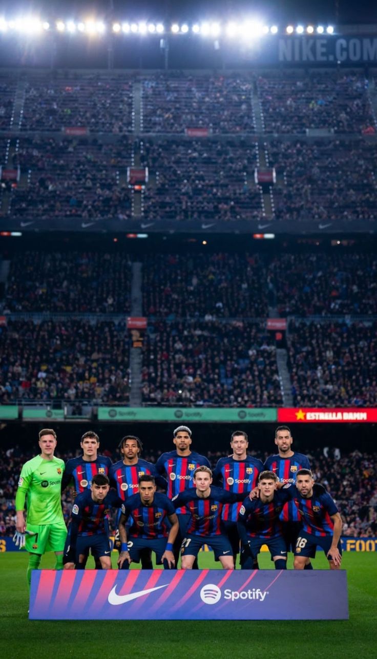 a group of men standing on top of a soccer field in front of a crowd