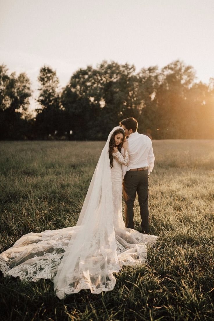 a bride and groom standing in a field at sunset with the sun shining on them