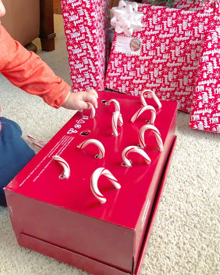 a young child playing with a red box filled with magnets in front of christmas presents